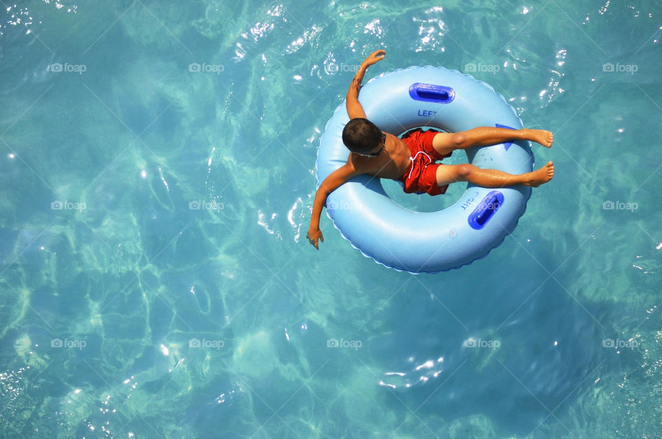 Early summer swimming. A young boy enjoys floating in a swimming pool.