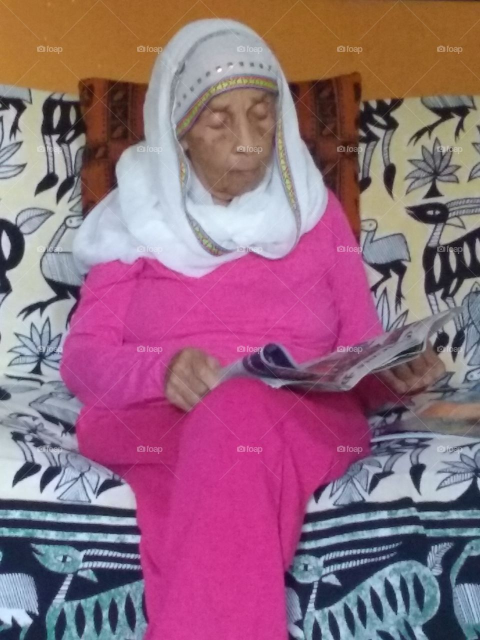 Senior woman reading news paper on sofa