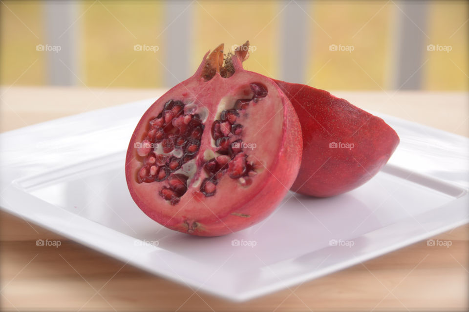 Exotic fruit, pomegranate, cut in half, white plate, seeds, red