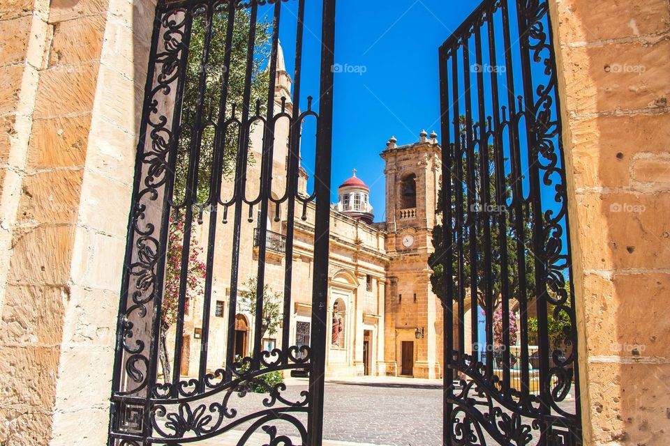 The Sanctuary of Mellieha framed by its ornate iron gates.