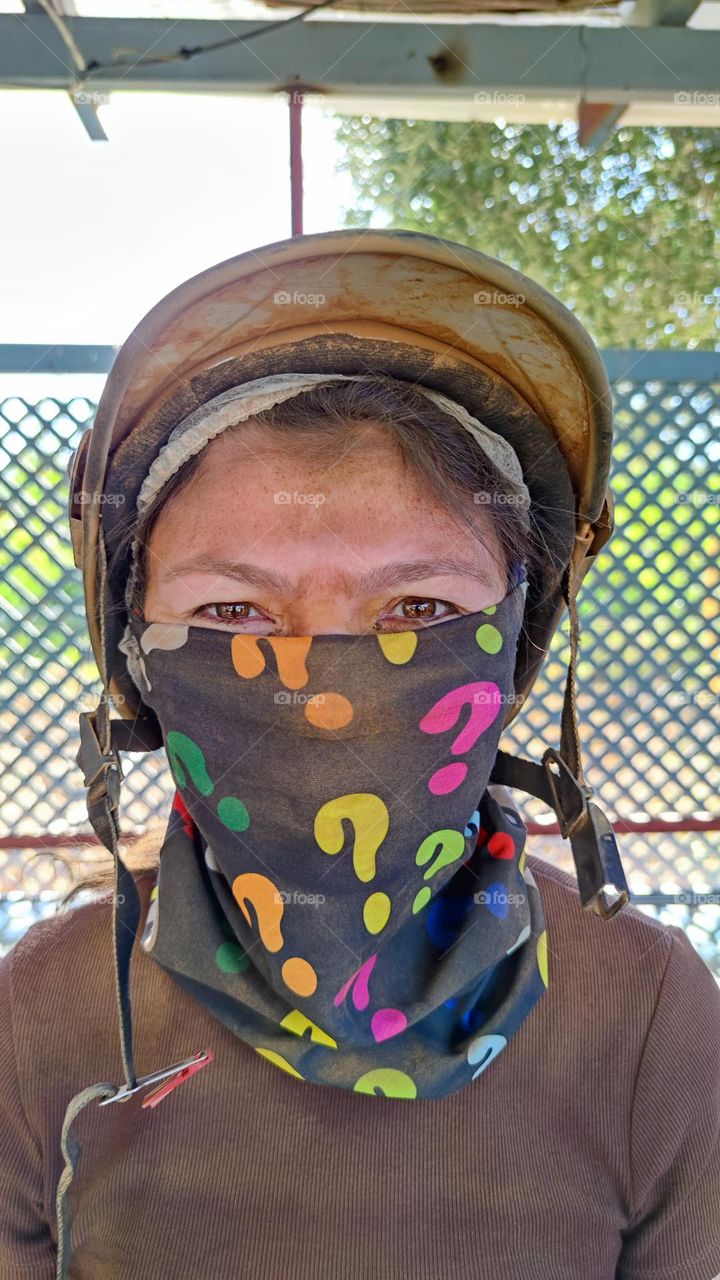 Portrait of one beautiful Caucasian young girl in a helmet with a bandage on her face in dirty and dusty clothes stands relaxing in the fresh air.