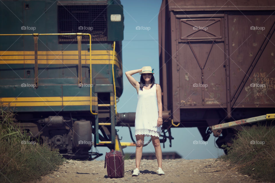 Woman standing in front of train with luggage bag