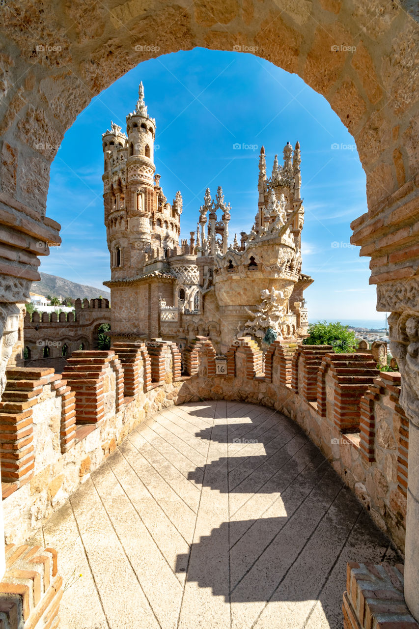 A beautiful shot of a fantasy castle through a stone archway found in Benalmadena, Spain