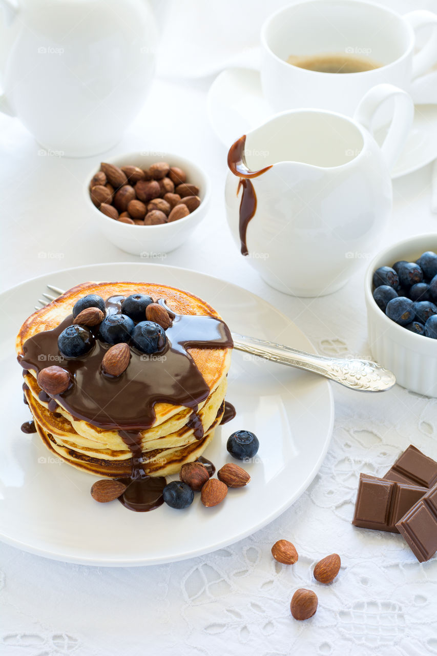 Stack of pancakes with chocolate sauce, blueberry and nuts. Healthy breakfast concept