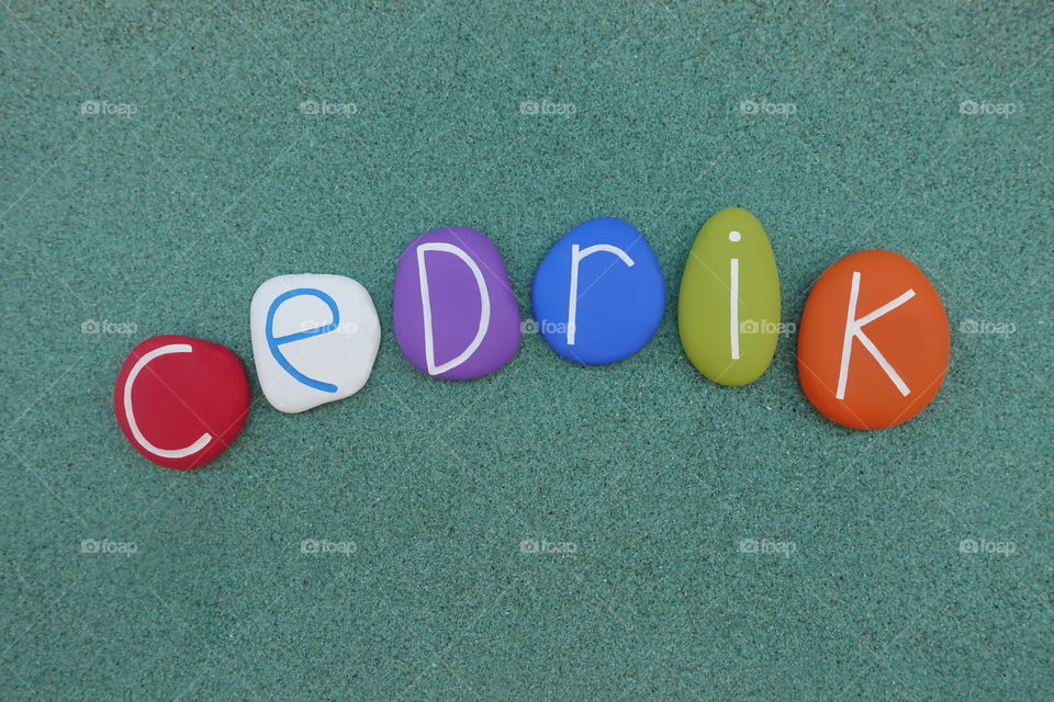 Cedrik, masculine given name composed with colored stones over green sand