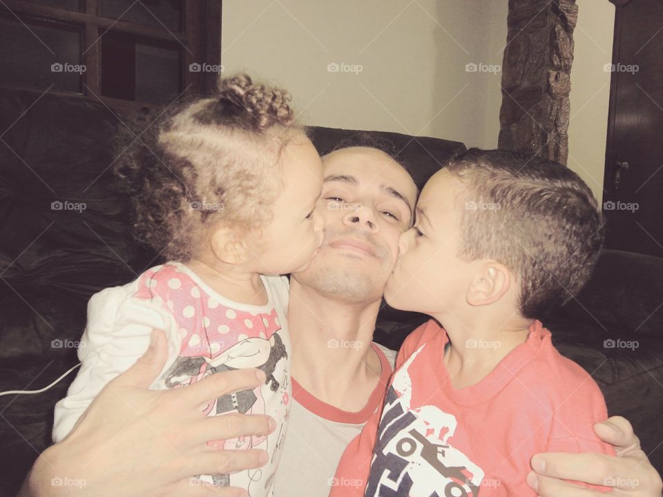 Children kissing their father on his cheek