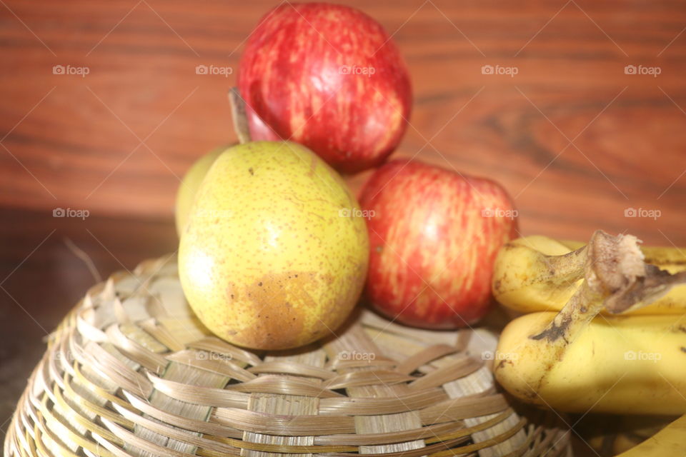 red apple with pear on basket with wood background