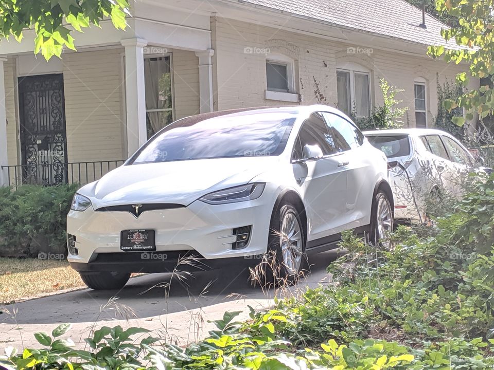White Tesla Model taking a drink to renew it's energy source at home.