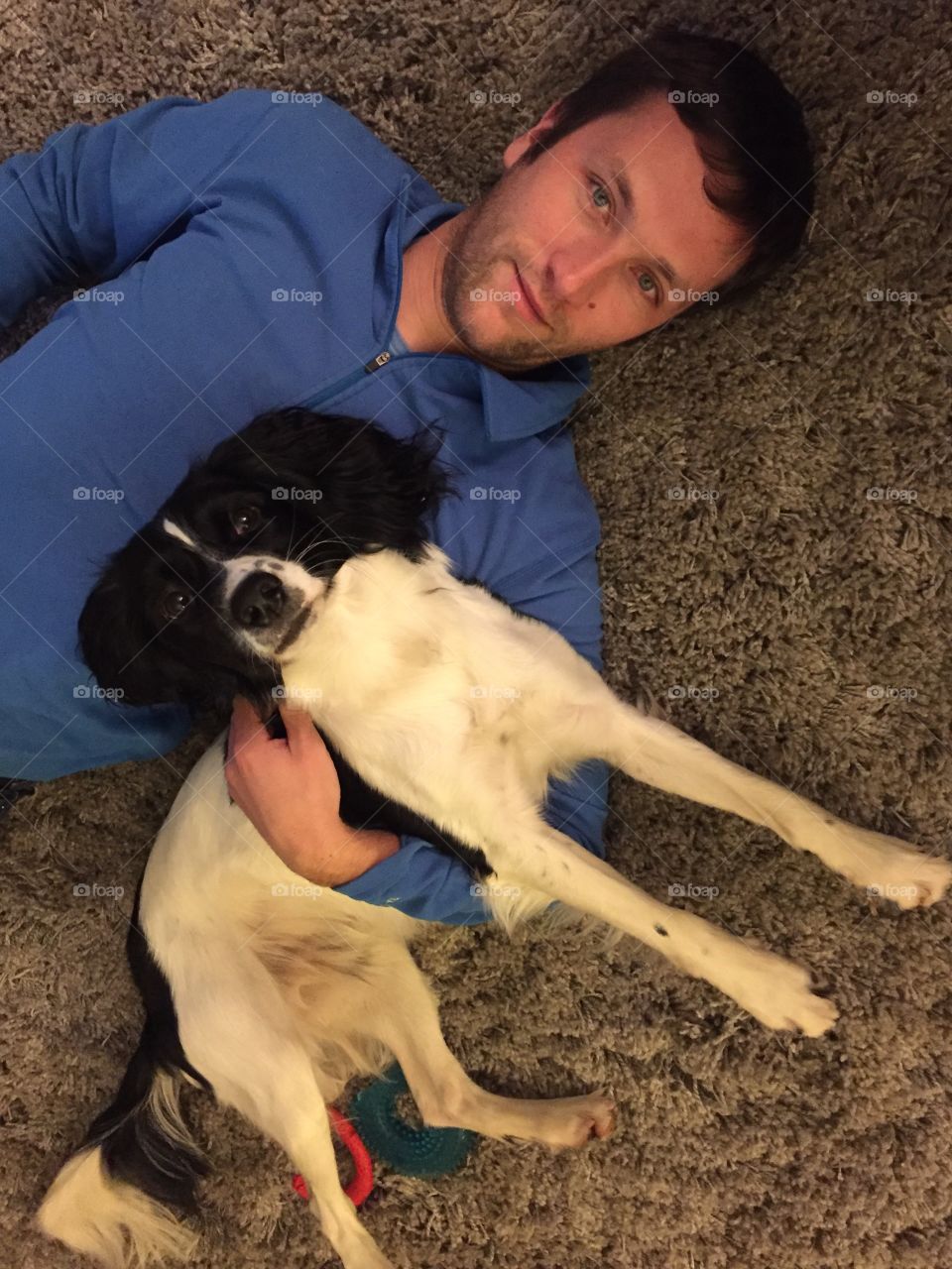 Elevated view of a young man lying on carpet with dog