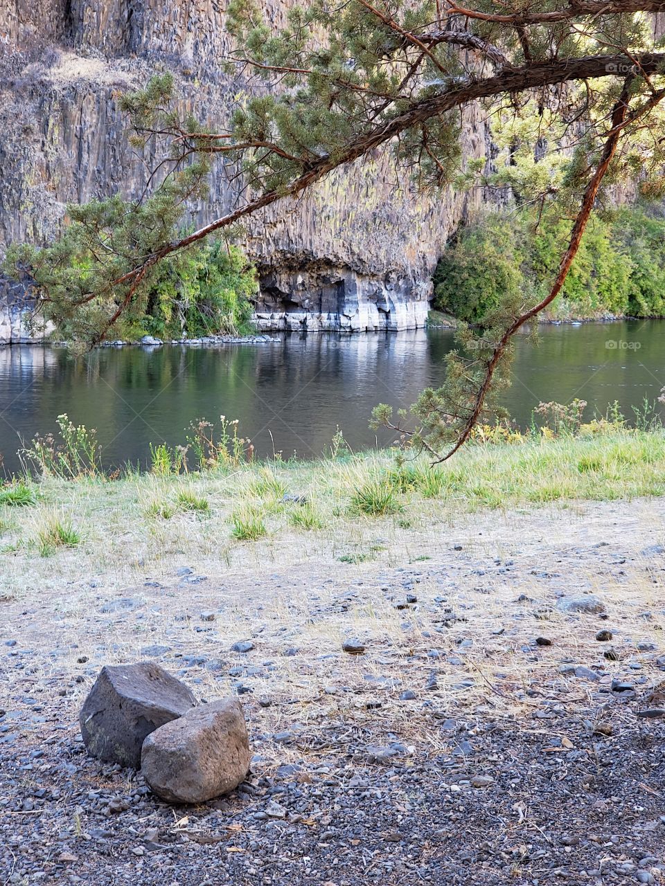 The beautiful Crooked River with fall colored bushes on its banks flows through a canyon formed from andesite and basalt flows on a nice autumn evening in Central Oregon. 