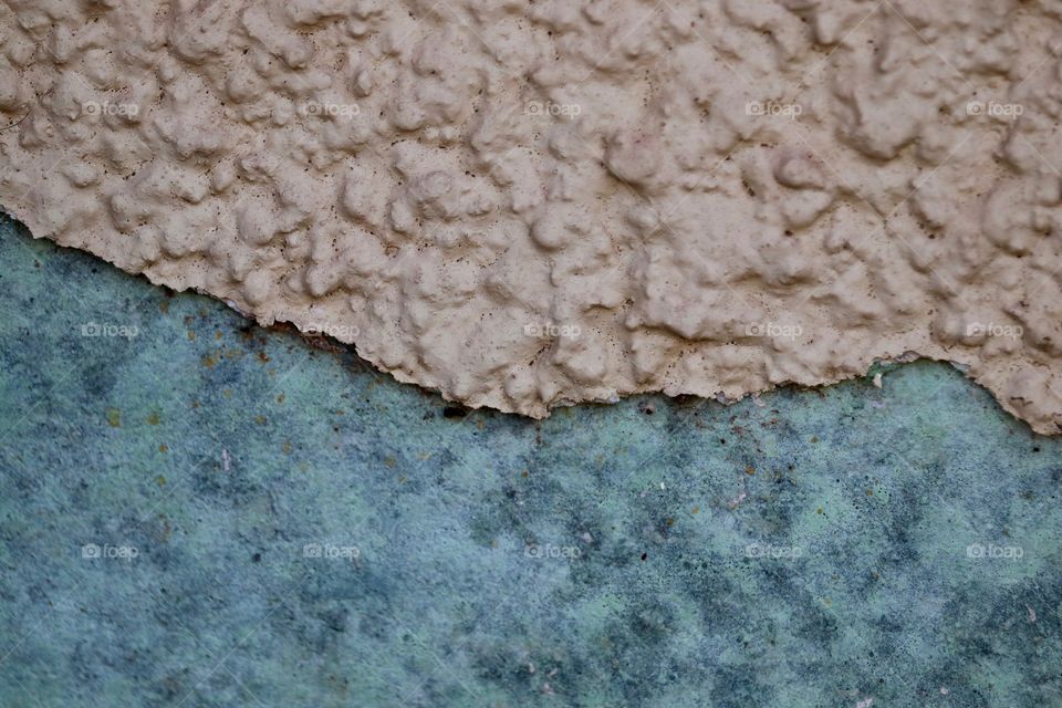 Stucco wall in disrepair showing original blue painted wall where stucco has lifted 