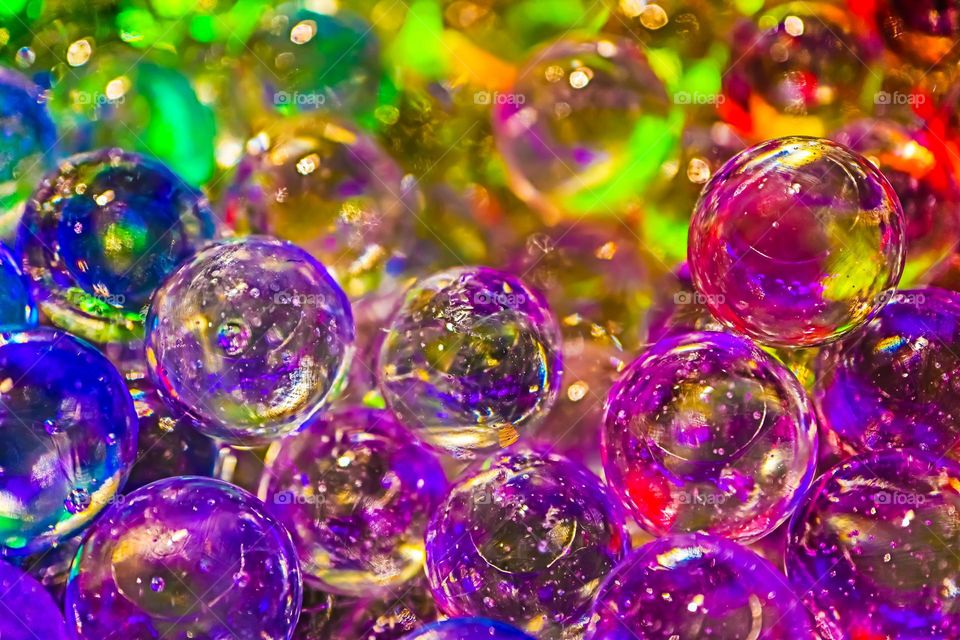 Colorful shiny glass marbles reflecting a rainbow of colors, closeup macro image 