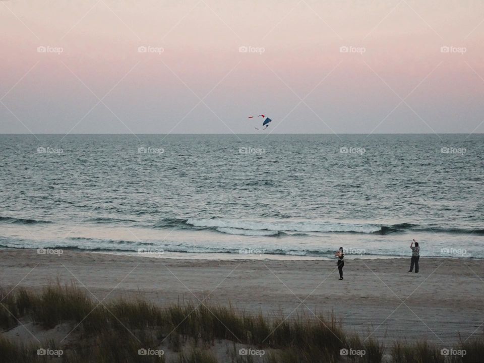 Two women playing a kite at Atlantic City New Jersey.