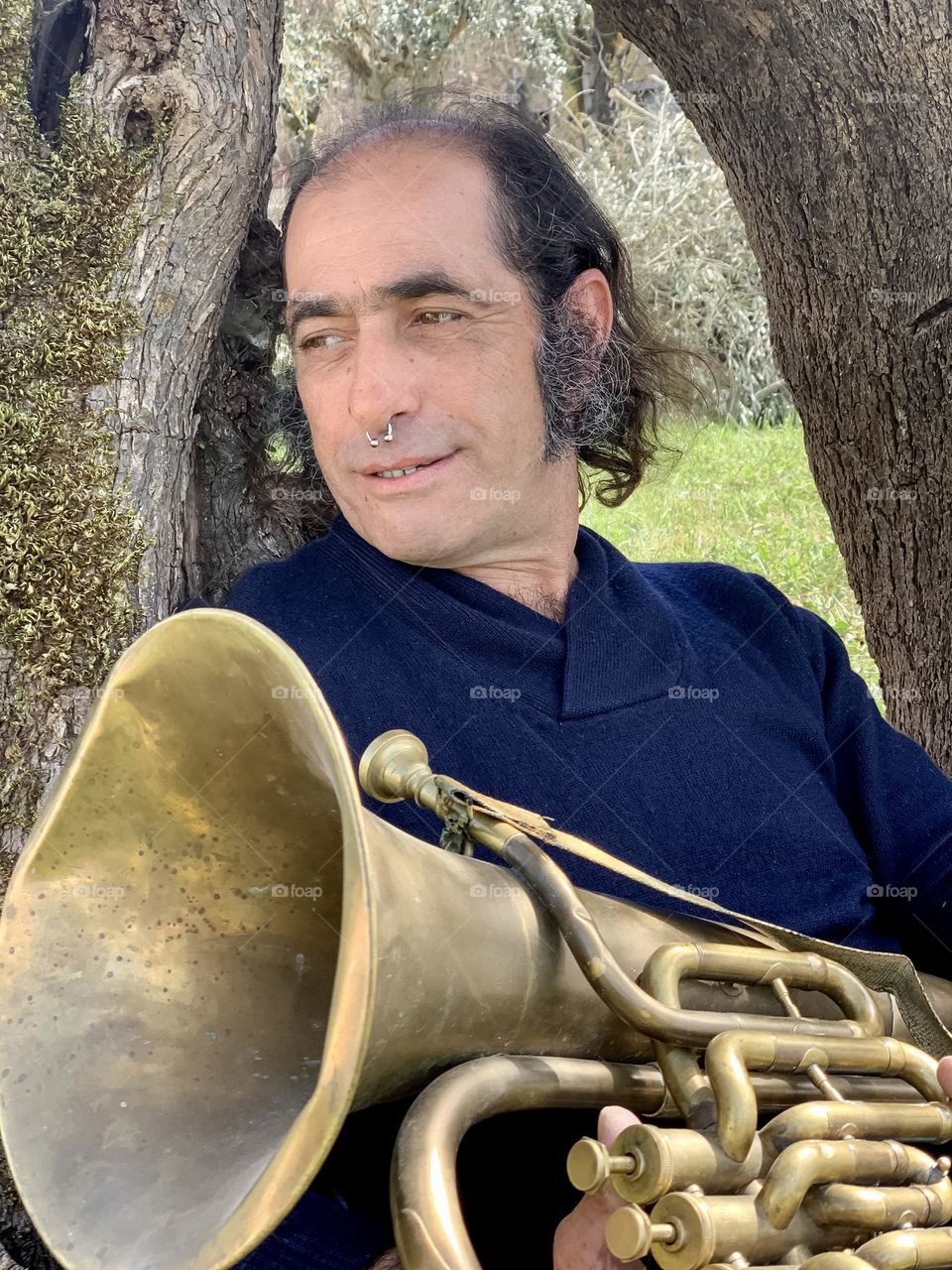 Portrait of Ricardo chilling out under a tree with his tuba 