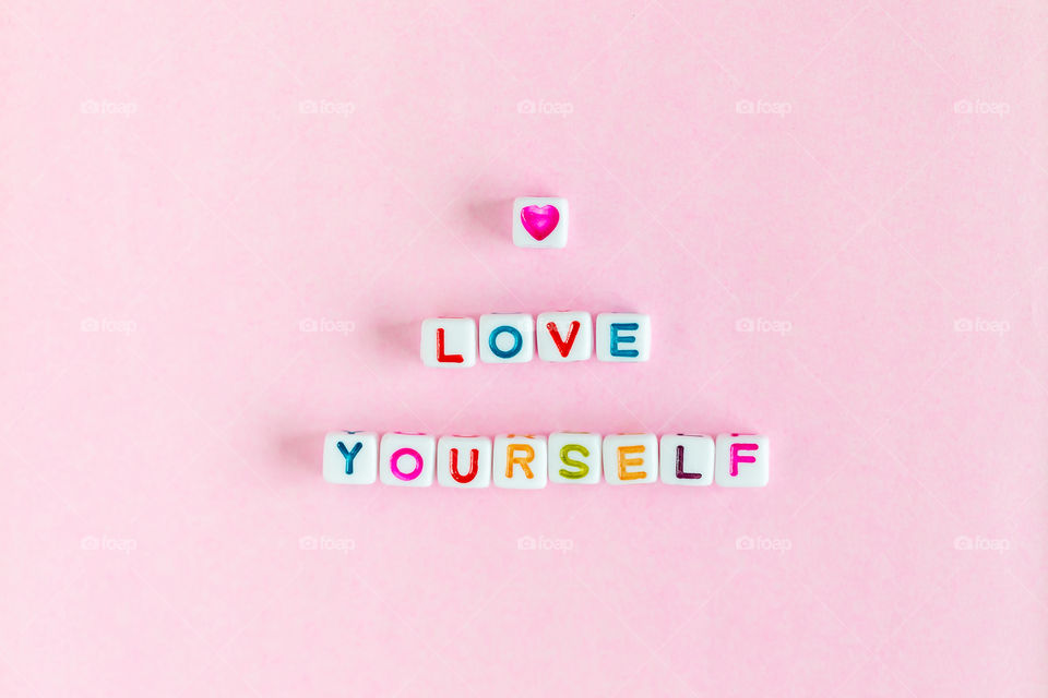 Motivational text "Love yourself". Text on pink background. Flatlay.