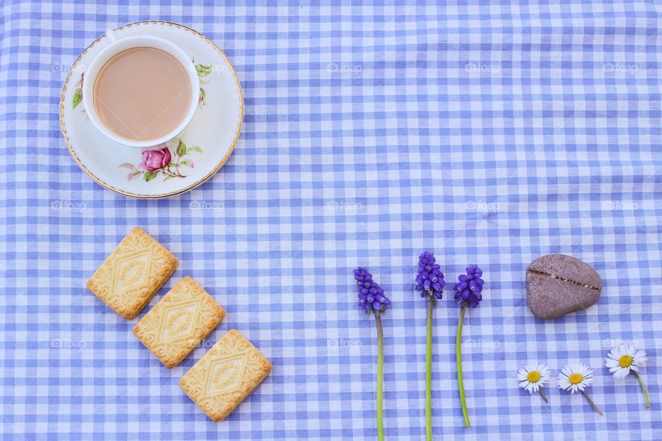 A cup of tea and wild flowers on a gingham tablecloth 