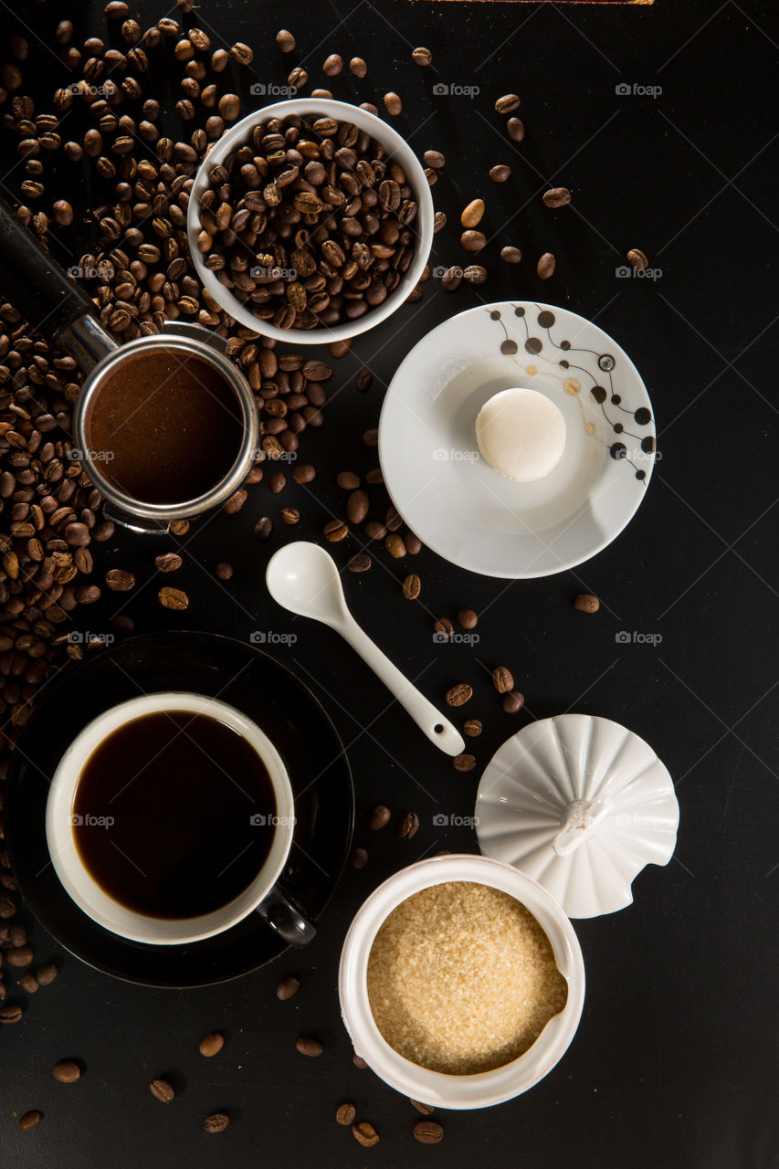 Coffee flat lay with beans and process from bean to cup on a black background