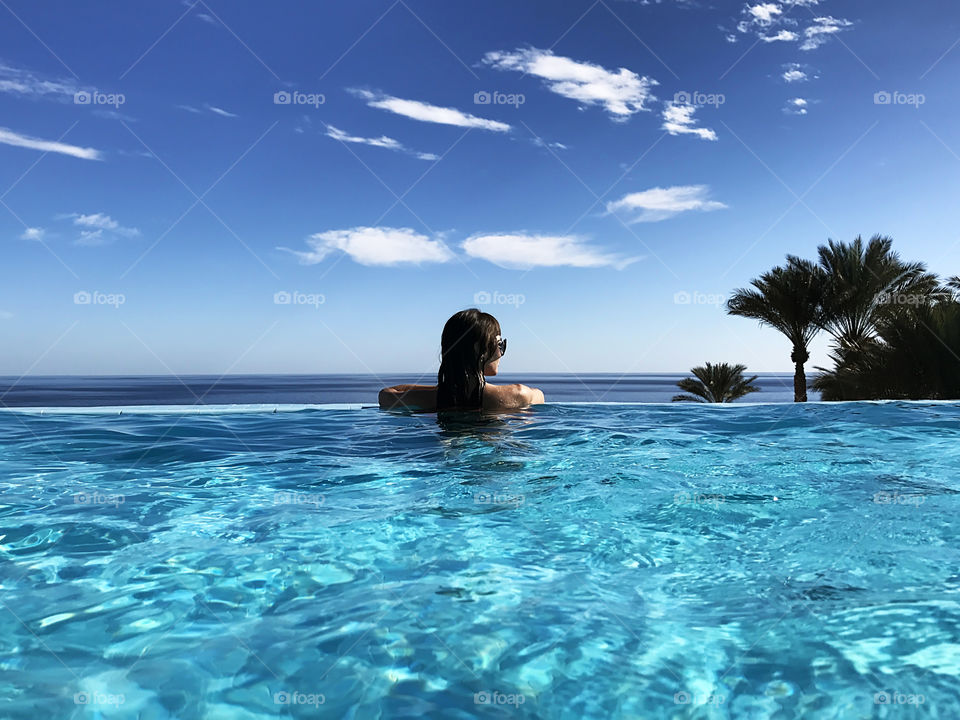 Young woman enjoying her summer tropical vacation by the swimming pool 