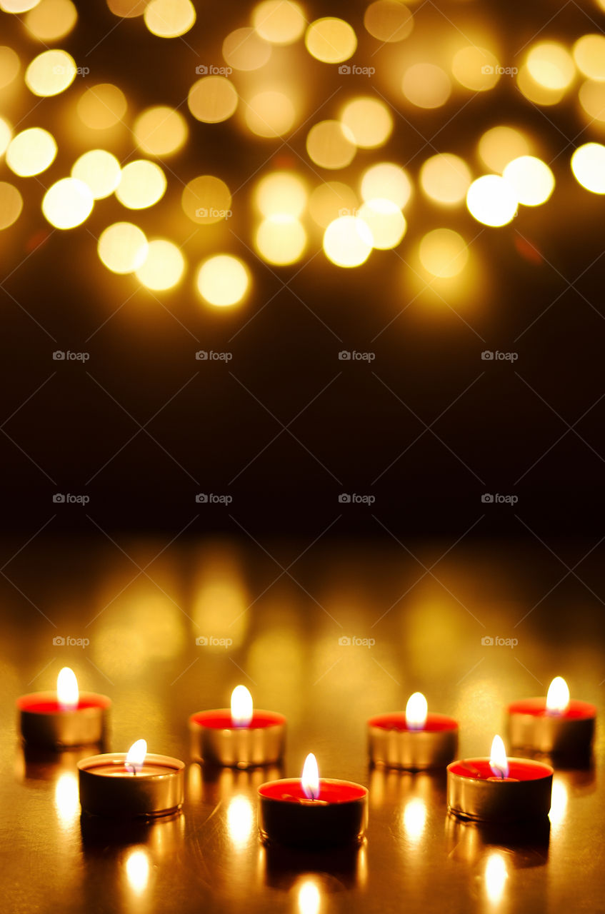 Burning candles with festive holiday bokeh background close up. Top view, flat lay. Christmas and holiday celebration concept. Hope and pray.