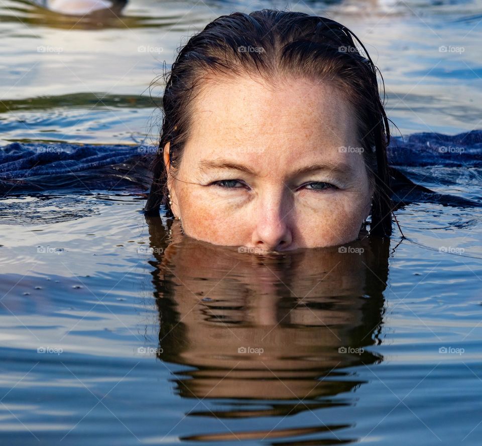 Mysterious woman ,maybe a mermaid, more under water that over . Reflection in the water.