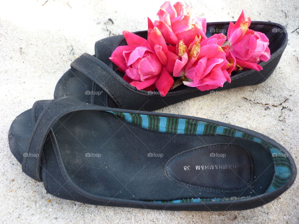 Shoes on the beach with rose petals