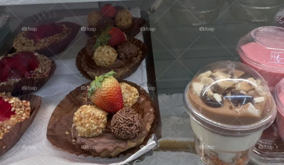 Docinhos comemorativos feitos com leite condensado e cobertura de granulados acompanhados com deliciosos morangos