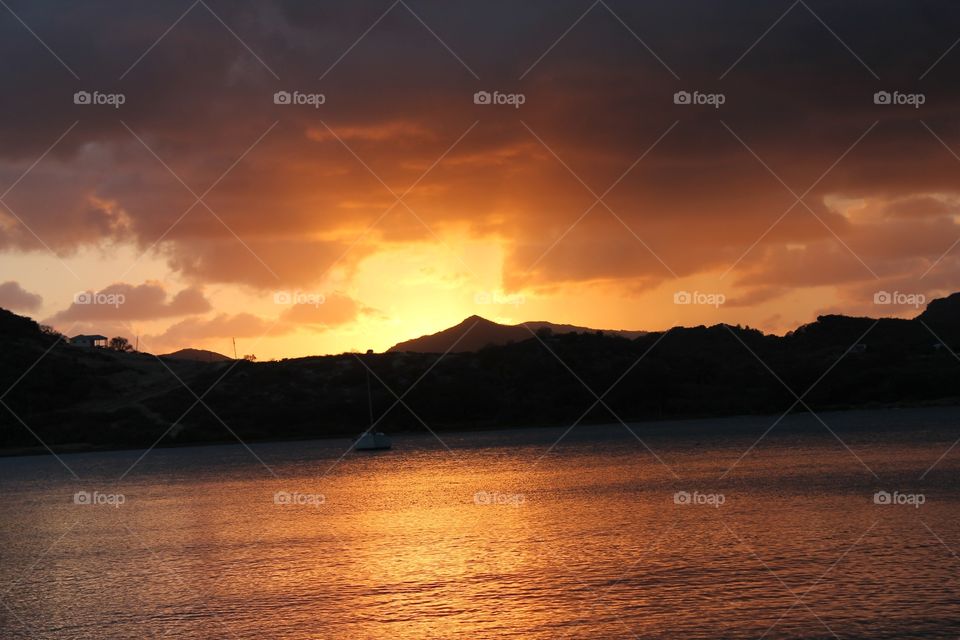 Sunset orange behind hills and ocean 