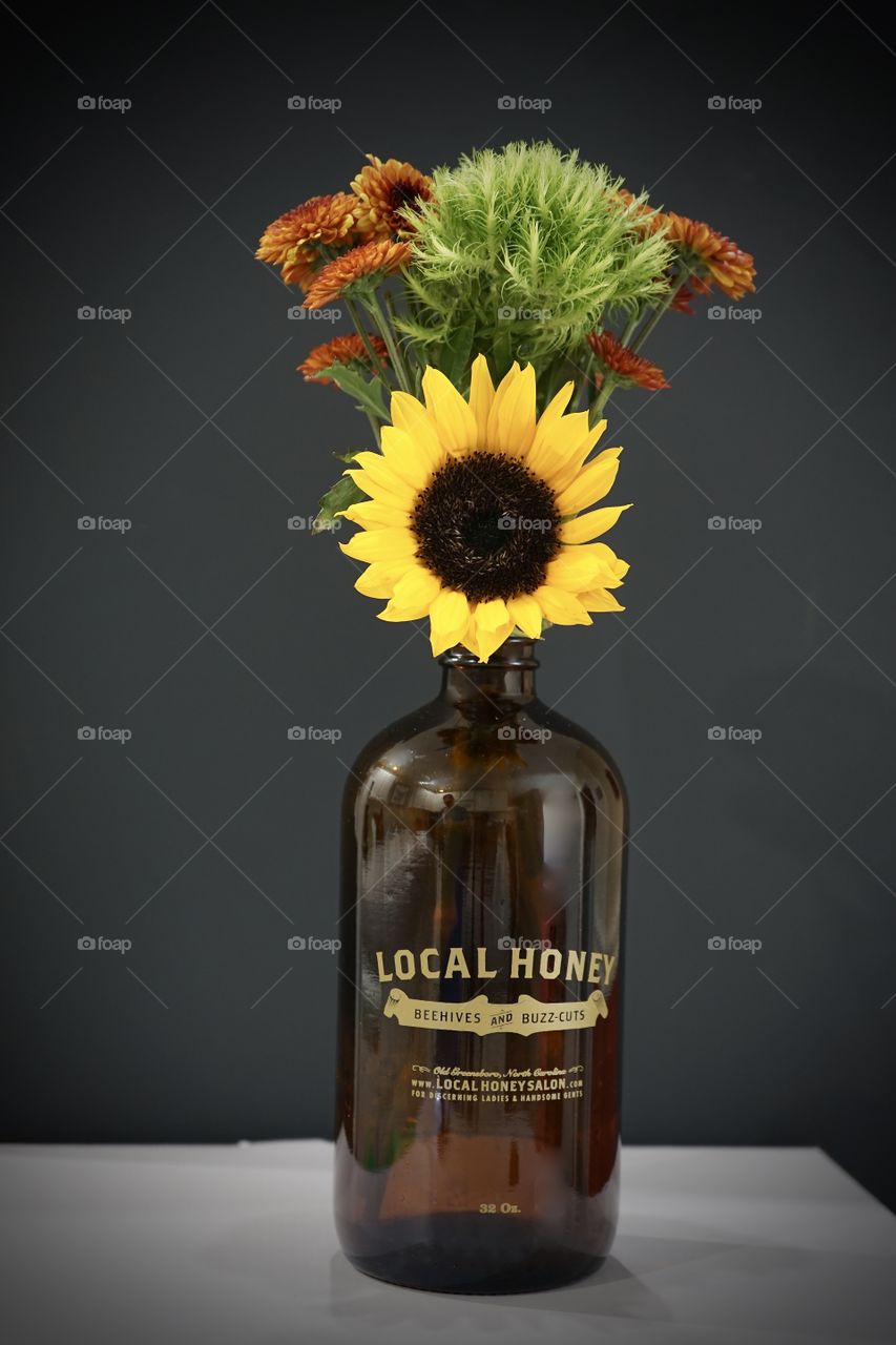 Brown growler with wildflowers against black background.