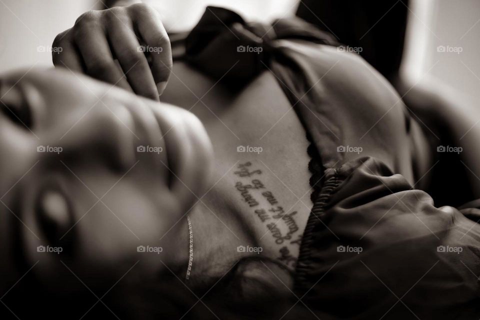 Samara and her tattoos looking up from the bed