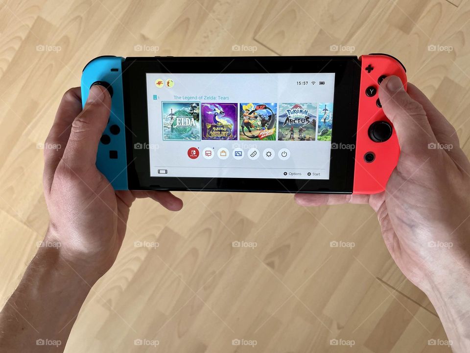 The Legend of Zelda: Tears of the Kingdom on Nintendo Switch gaming console held by male hands. This is a sequel to the game Breath of the Wild