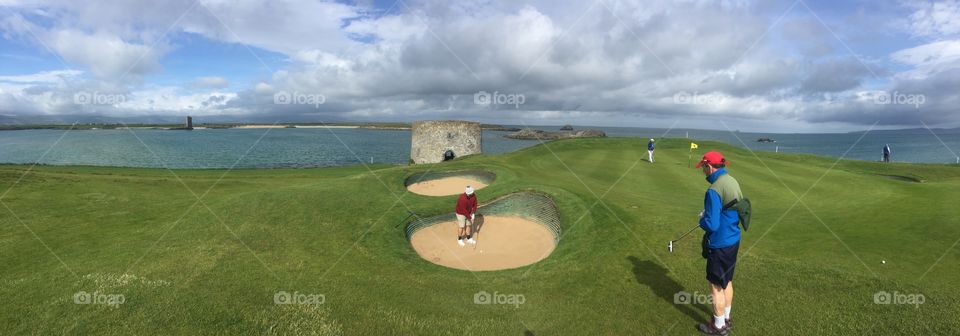 Bunker shot in Ireland at Tralee golf club. Golfer preparing to hit a sand shot onto the green