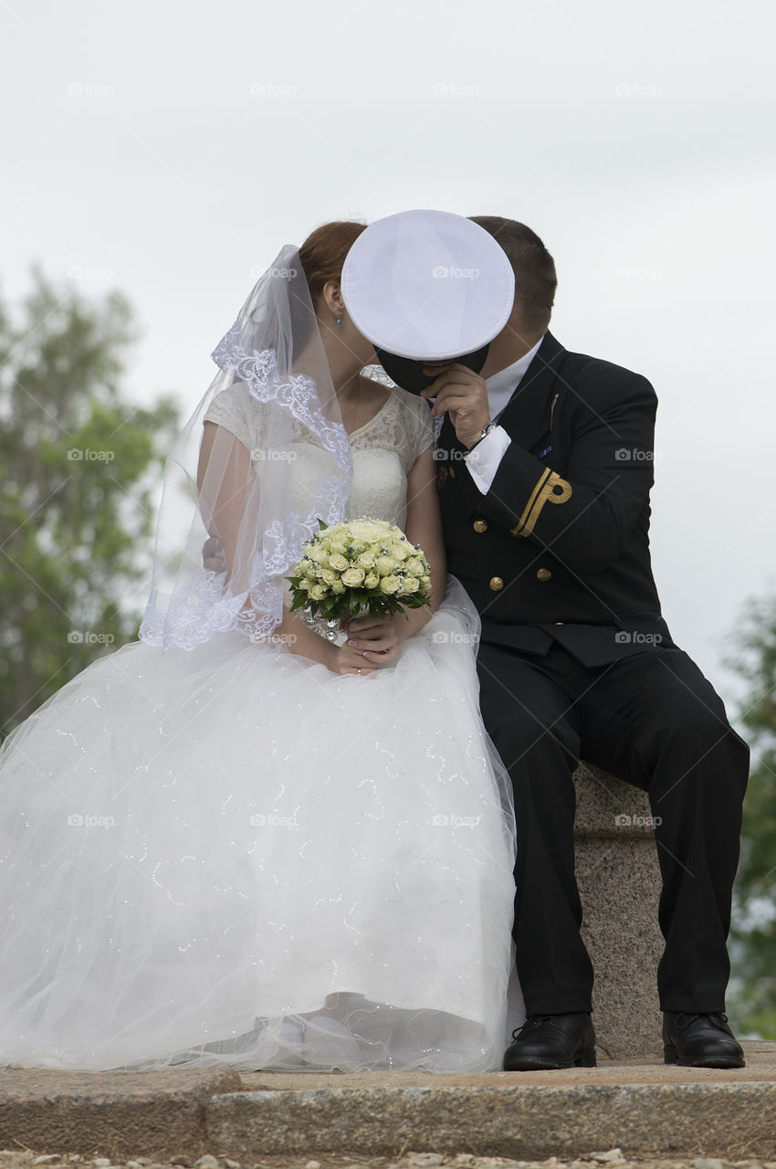 Wedding couple kissing and hiding behind the cap