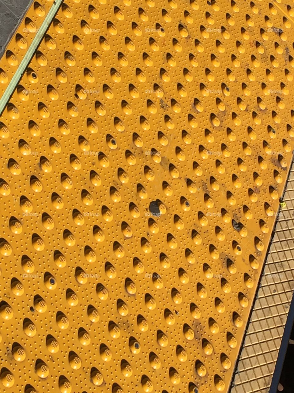 Yellow pavement on the train platforms . Yellow bumps separates waiting passengers from train.