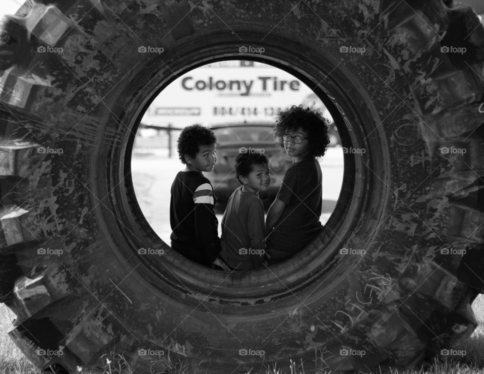 Three brothers sitting inside an oversized tire