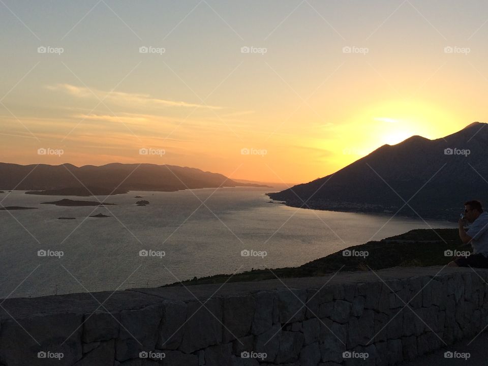 Sun setting behind the mountain by the sea