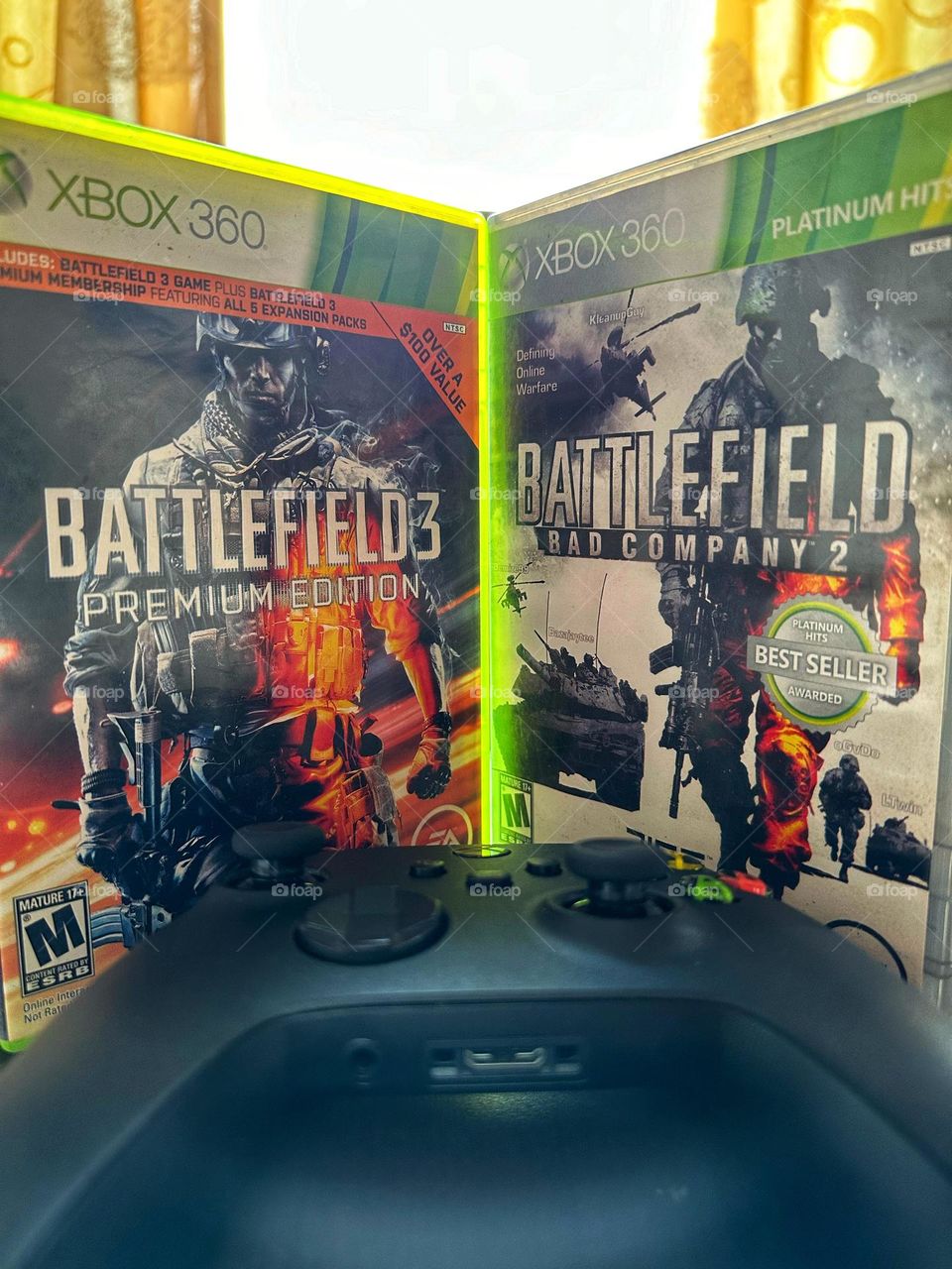 Battlefield boxes side by side with a Xbox controller in the middle of them with natural light.