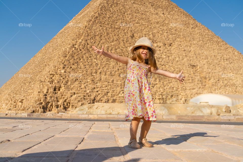 Cute little girl dancing in front of the Cheops pyramid on the Giza plateau.