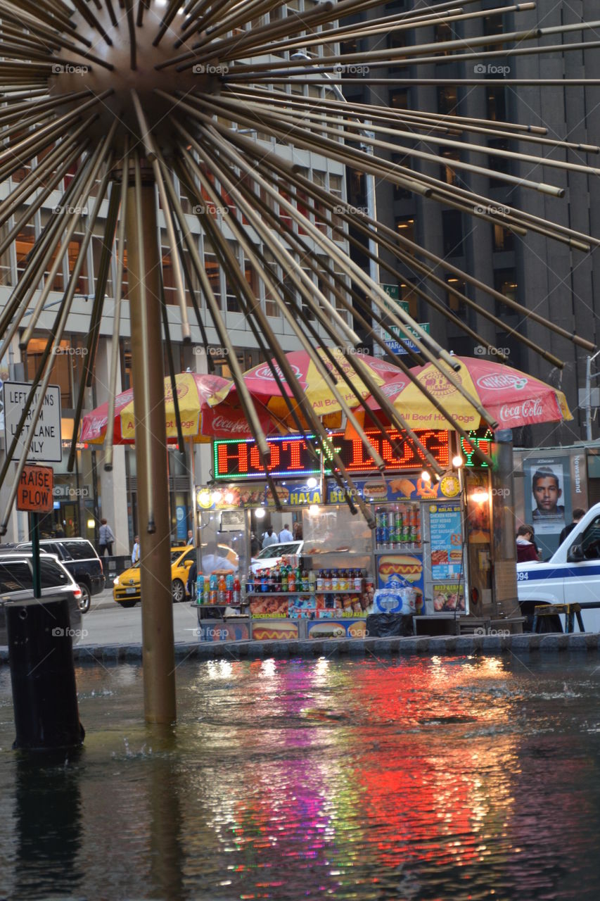 New York City  hot dog cart at dusk with a reflection in a fountain