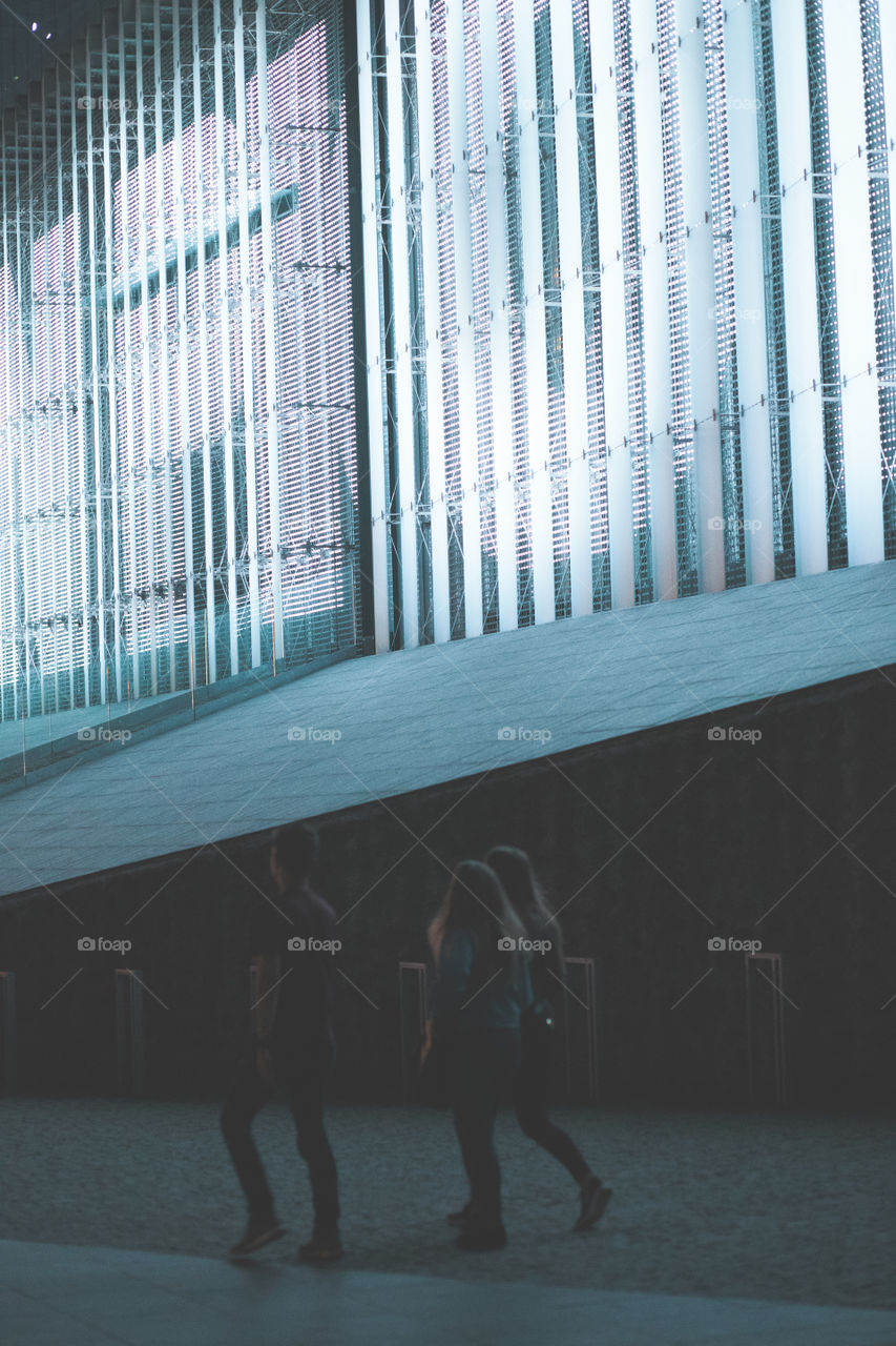 Group of people walking in a center of city at night. Backlit construction behind them