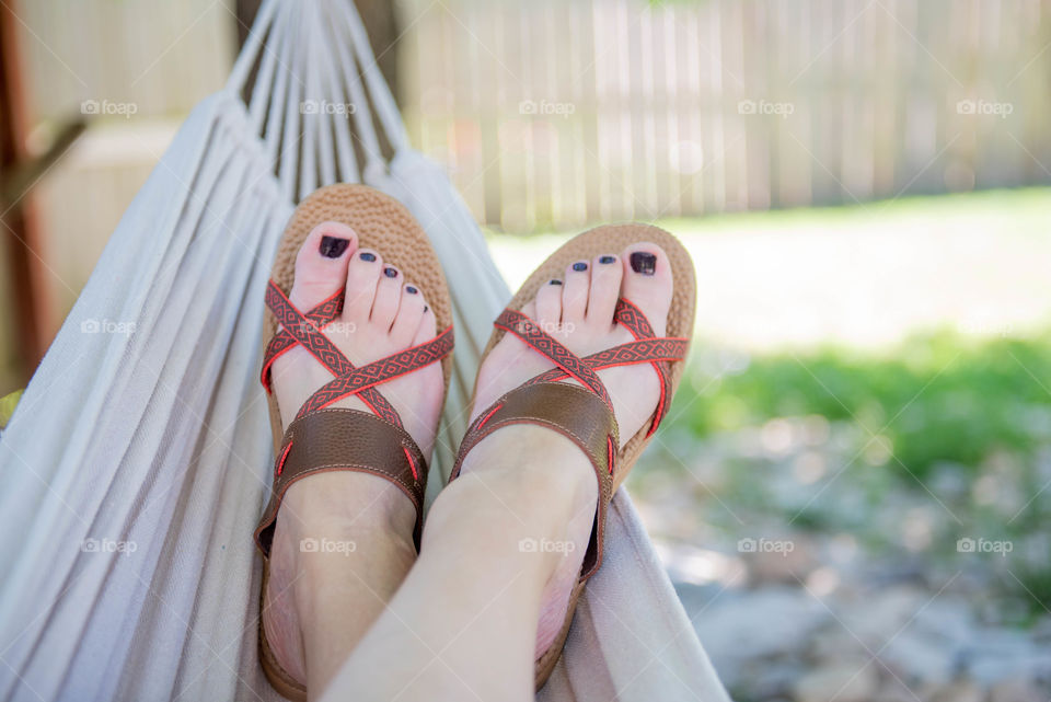 Close-up of a woman's feet wearing sandals and resting in a hammock