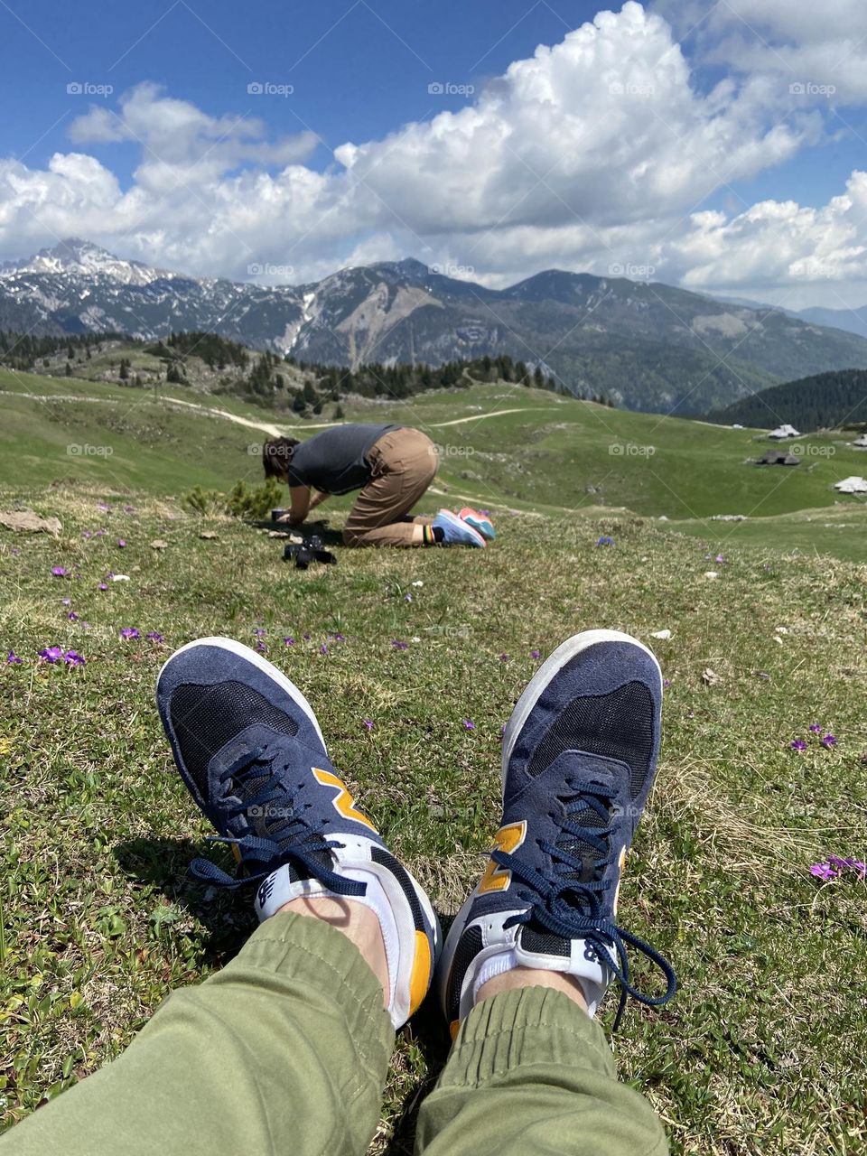 Backstage of the photo shooting in the beautiful Alps mountains in spring in Slovenia.  Young woman photographer doing photos on her phone, camera