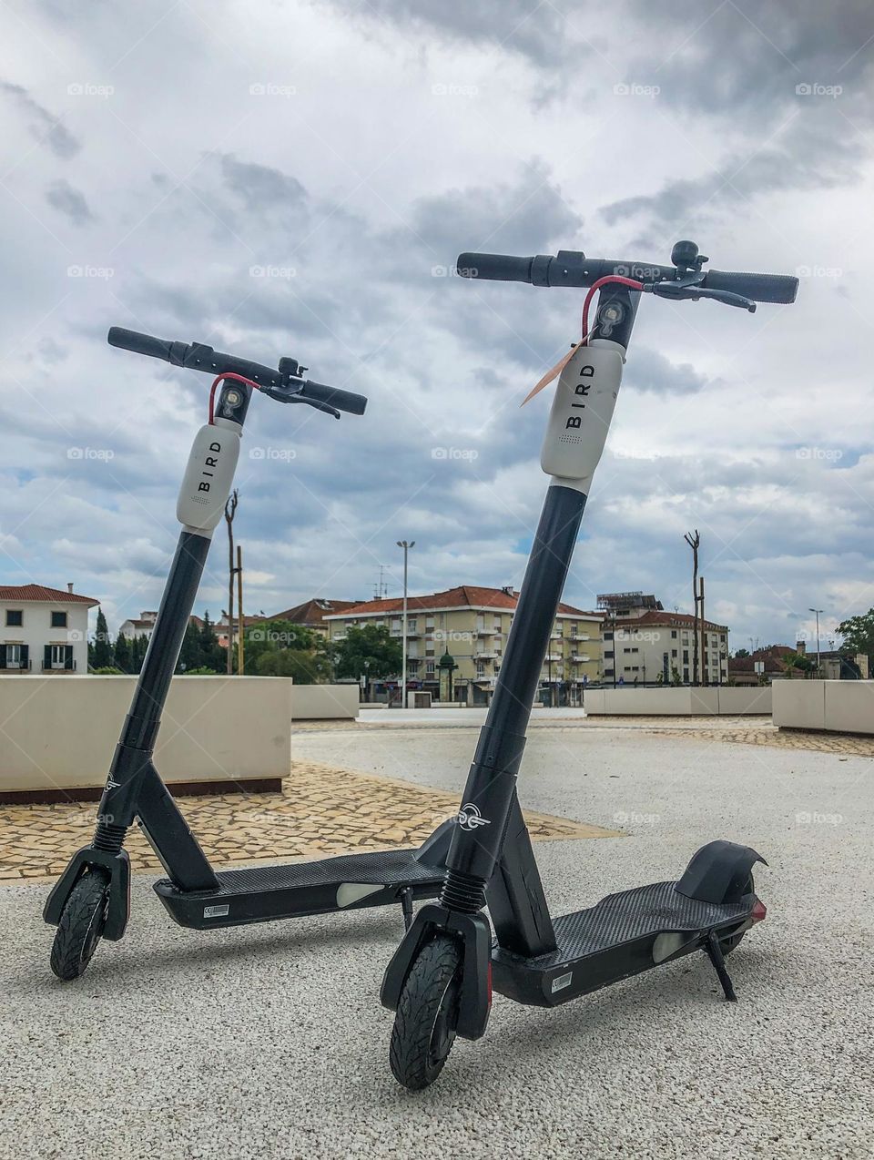 2 scooters available for public use, sit in a town square