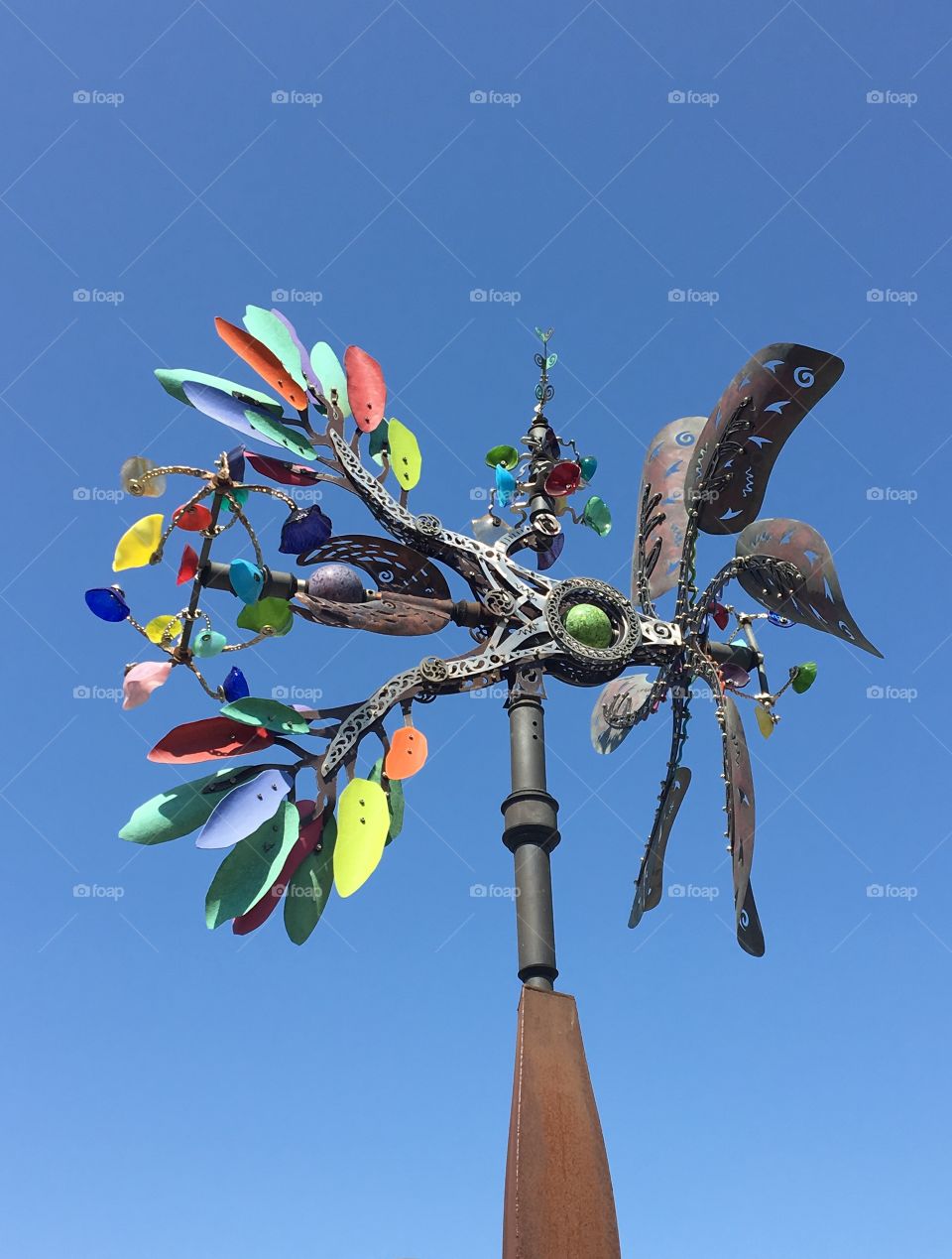 A creative, colorful, artsy wind mill turning from the breeze and a blue sky