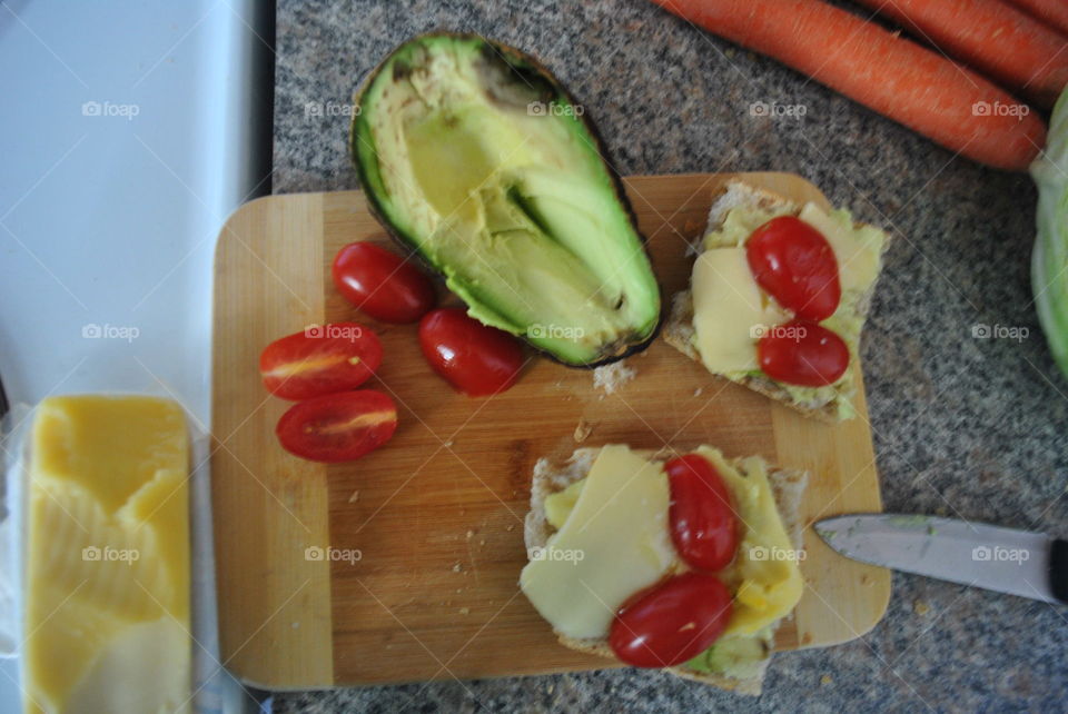 Making small sandwiches with cheese, avocado and cherry tomatoes