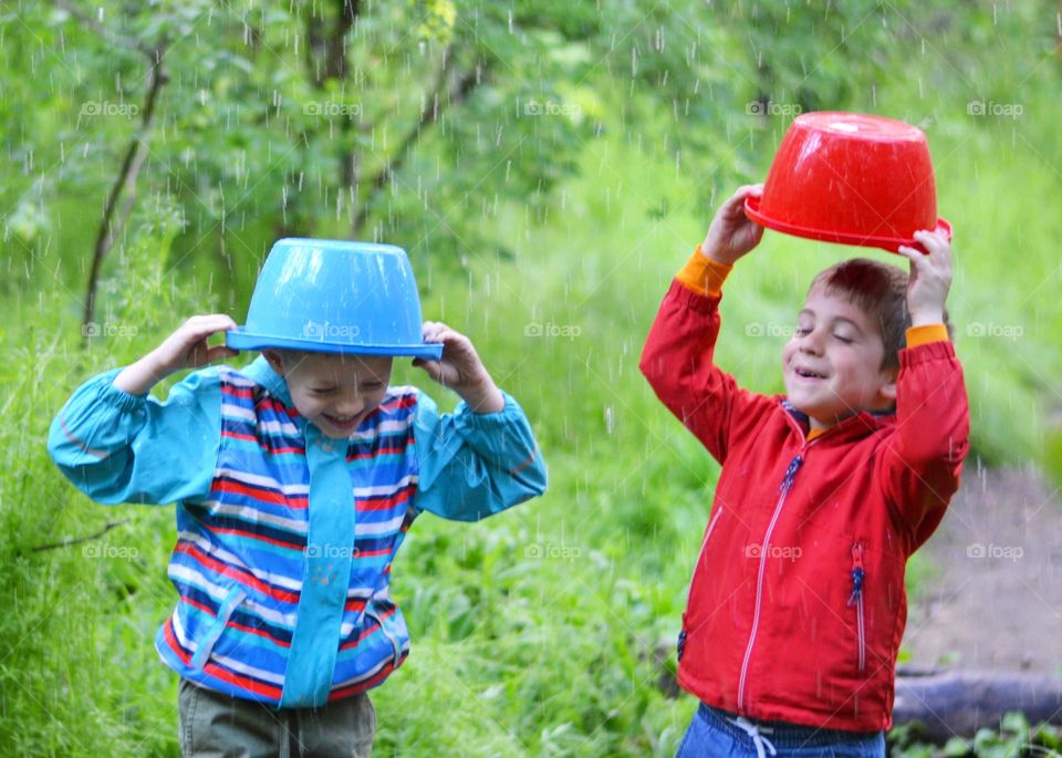 Children Playing in Rainy Spring Day with Buckets on Their Heads