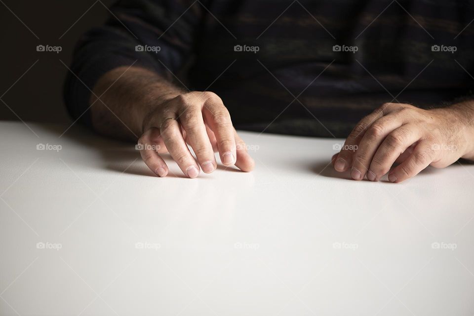 A man's hands on an empty table surface