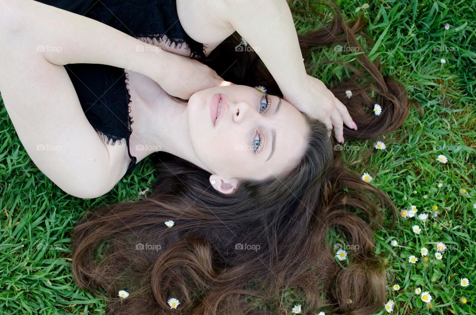 Portrait of Beautiful Young Girl on Background of Daisies