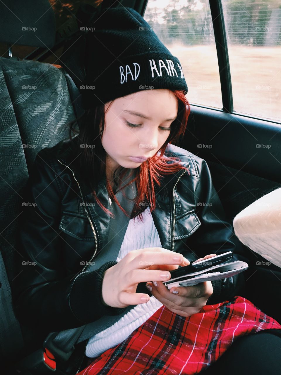 Girl with a phone sitting in the car