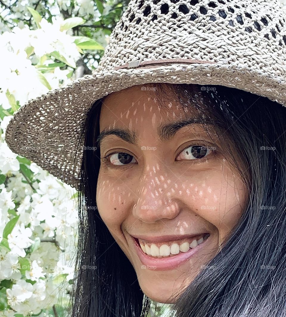 Portrait of smiling woman with no make up. Wearing grey hat. Spring background.