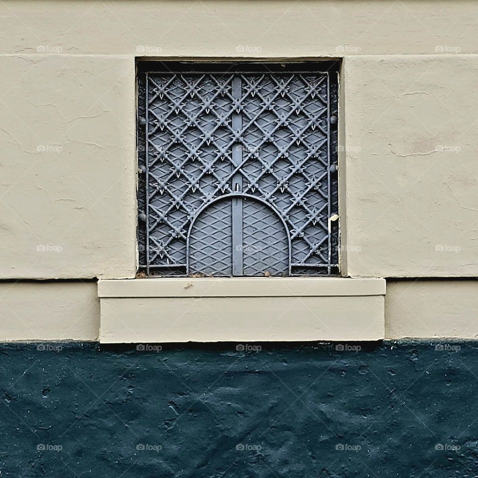 Exquisite iron work on window frame, intricate design, and handywork. This small window is one of many box offices at the entrance of a the racetracks.